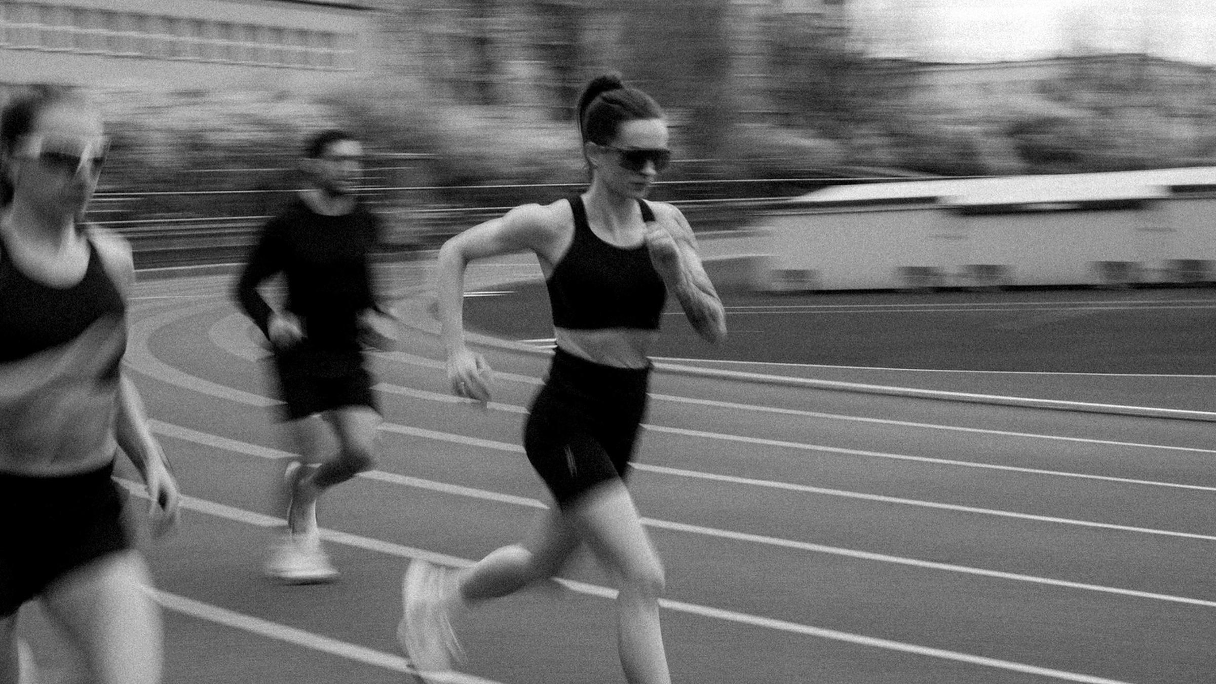 Weronika Pietras biegnie z&nbsp;dwojgiem biegaczy po łuku bieżni stadionu, sesja zdjęciowa atletów nuvr, kwiecień 2026